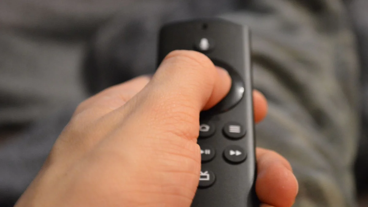 A person's hand holding a TV remote control in Berlin, Germany, illustrating iptv box all channels free