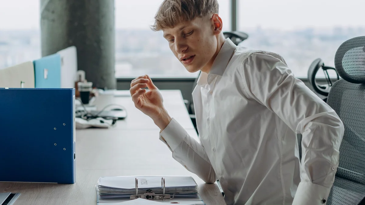 Man in white shirt sitting at office desk reading documents, modern workspace, illustrating is tivimate legal