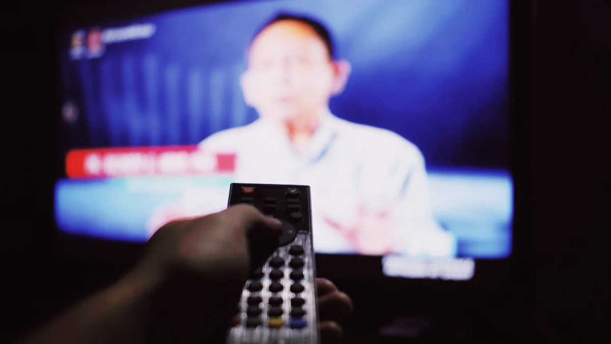 Anonymous person with remote controller switching channels while watching TV, illustrating live sports m3u playlist