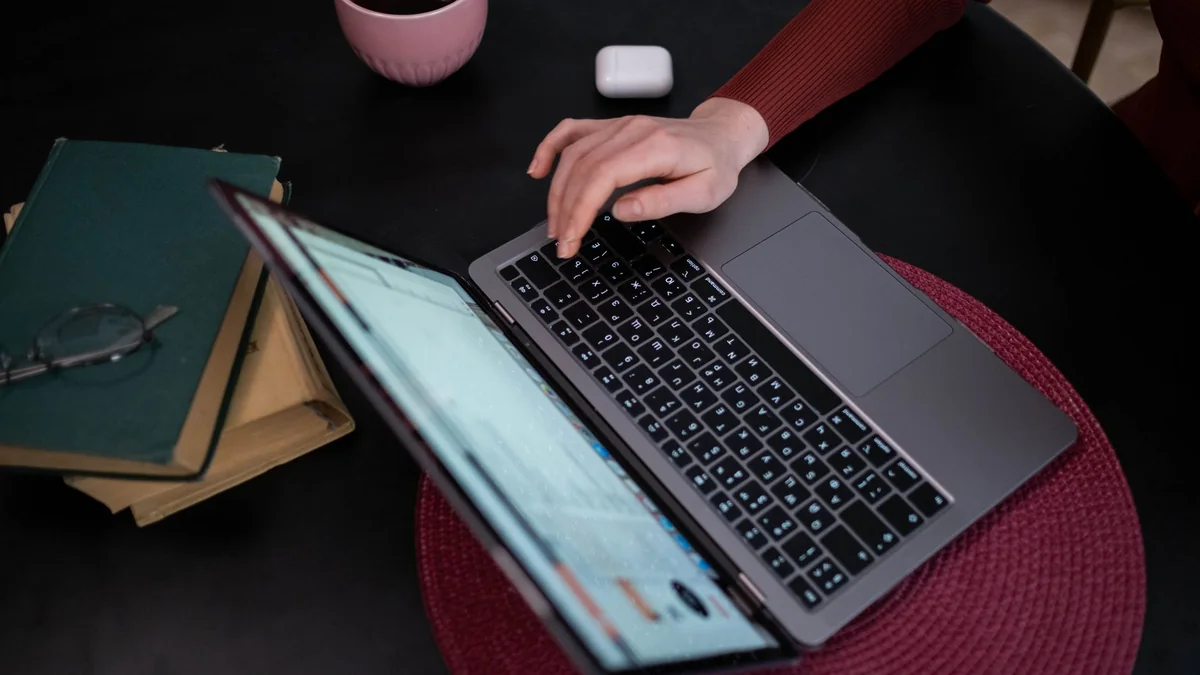 A person typing on a laptop with coffee and books nearby, creating a cozy work, illustrating public iptv stream url